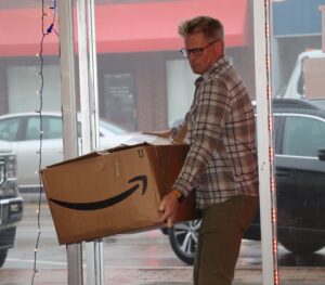 Aaron Gindt carries a box of dresses into Harmony Clothing Closet.