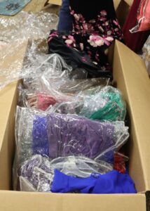 Dresses from one opened box are shown as they await sorting.