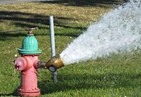 A hydrant being flushed is shown with water spraying out.