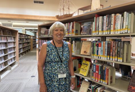 Julie Ungs stands by a book shelf inside the Nevada Public Library.