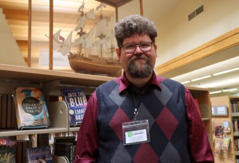 Derek Grote poses in front of a book case in the Nevada Public Library.
