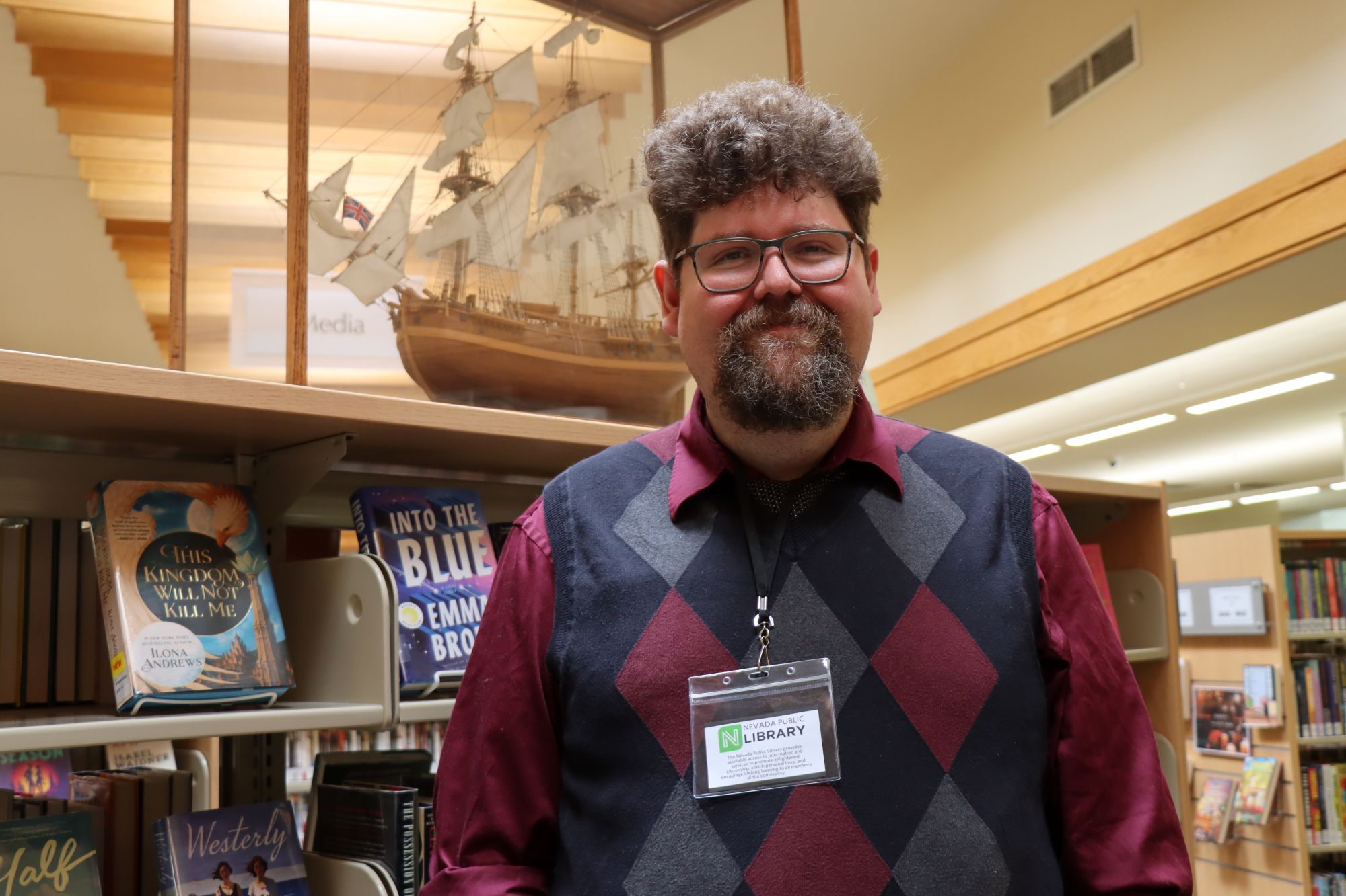 Derek Grote poses in front of a book case in the Nevada Public Library.